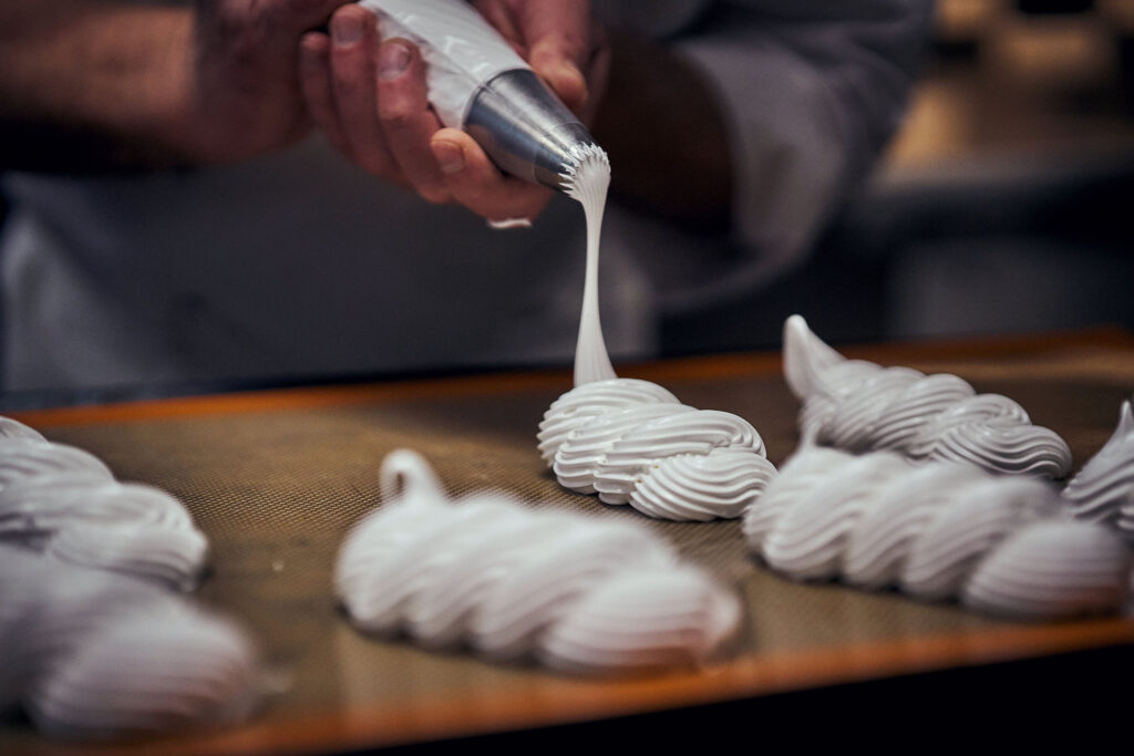 Un stagiare de la formation dresse des meringues blanches à la poche à douille pendant une formation de pâtisserie à l’Institut Lyfe Executive Education.